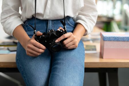 Mid section of Caucasian female graphic designer holding digital camera in a modern office. This is...