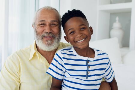 Portrait close up of African-American boy and mixed race man smiling inside a room. Authentic Senior...