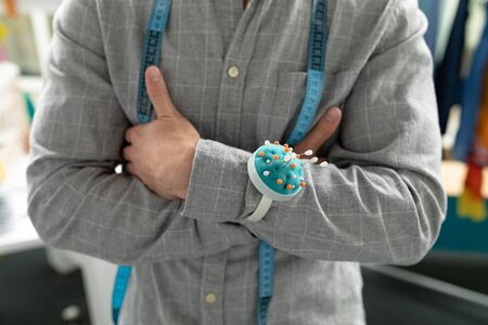 Mid section of Caucasian male fashion designer standing with arms crossed in design studio. This is...