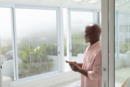 Side view of African American Thoughtful man using smartphone. Authentic Senior Retired Life Concept