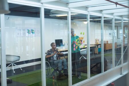 Side view of diverse executives discussing together over sticky notes in office. This is a casual...