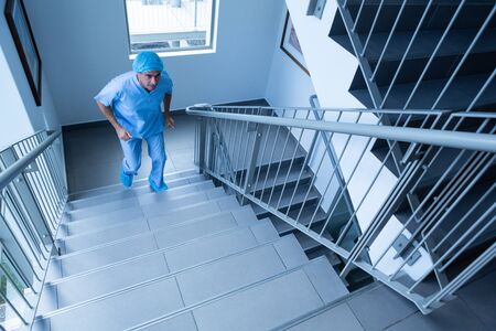 High angle view of Caucasian male surgeon walking upstairs quikly in hospital. Shot in real medical...