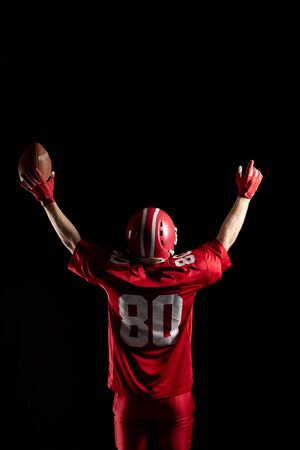 Rear view of American football player cheering with arms up. Strong American Football Player concept for Championship Football Tournamentの写真素材