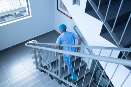 High angle view of Caucasian male surgeon running upstairs in hospital. Shot in real medical...