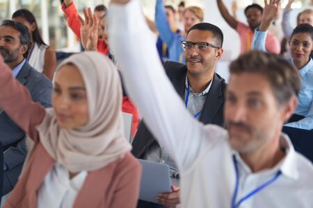 Close-up of diverse audience raising their hands in a business conference. International diverse corporate business partnership conceptの写真素材
