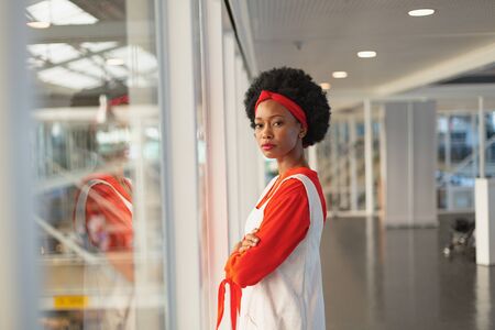 Portrait of beautiful young confident mixed race businesswoman standing with arms crossed in modern...