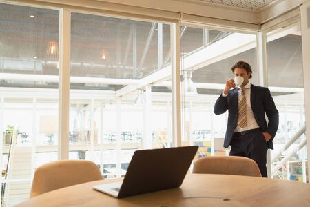 Front view of handsome young Caucasian businessman having coffee in the conference room at office. New start-up business with entrepreneur working hardの写真素材