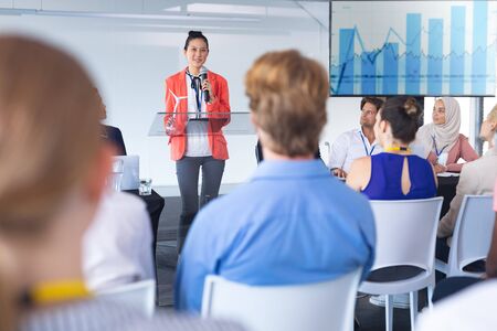 Front view of Asian female speaker speaks in a business seminar. International diverse corporate...