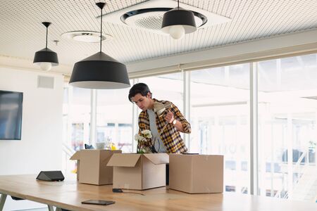 Front view of handsome young Caucasian male executive unpacking cardboard box in the conference room at office. New start-up business with entrepreneur working hardの写真素材