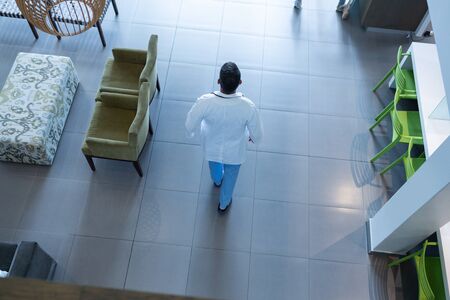 High angle of Caucasian male doctor walking in lobby at hospital. Shot in real medical hospital with...