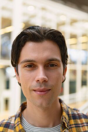 Portrait close-up of happy handsome Caucasian male executive standing in the corridor at office. New...