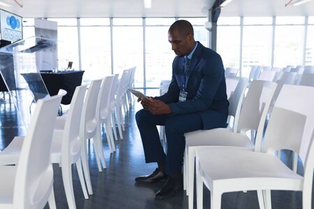 Side view of African-american Male speaker practicing his speech on digital tablet in business...