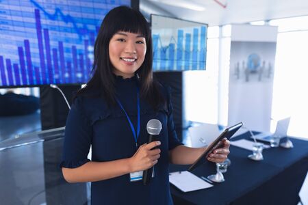 Portrait of asian female speaker with digital tablet speaks in business seminar. International diverse corporate business partnership conceptの写真素材