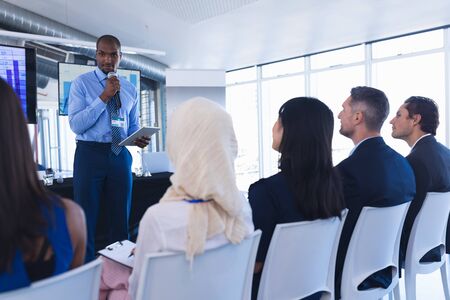 Front view of caucasian Male speaker with digital tablet speaks in business seminar at conference...
