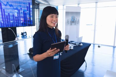 Side view of asian Female speaker with digital tablet speaks in business seminar at conference...