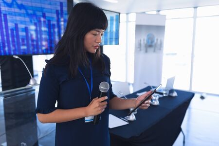 Side view of asian Female speaker with digital tablet speaks in business seminar at conference...