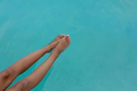 Low section of Caucasian woman's feet in swimming pool. Summer fun at home by the swimming pool