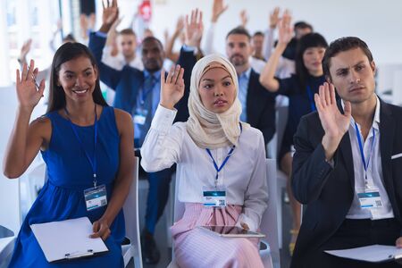 Front view of diverse Business people raising their hands while attending business seminar in...