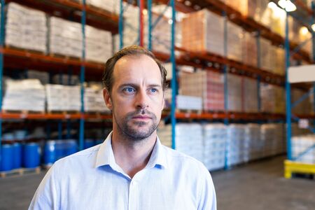 Portrait close-up of handsome mature Caucasian male supervisor looking away in warehouse. This is a freight transportation and distribution warehouse. Industrial and industrial workers conceptの写真素材