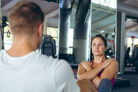 Side view of young fit Caucasian male and female athletic exercising together in fitness center....