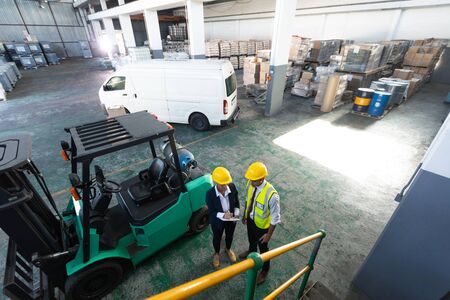 High angle view of Caucasian female manager and male supervisor discussing over clipboard in...