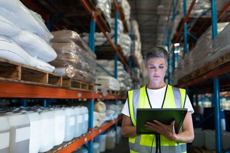 Front view of Caucasian Attentive female staff using digital tablet in warehouse. This is a freight...