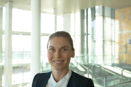 Happy businesswoman looking at camera in a modern office building. Modern corporate start up new...