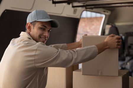 Close-up of delivery man unloading cardboard boxes from a van outside the warehouse. This is a freight transportation and distribution warehouse. Industrial and industrial workers conceptの写真素材