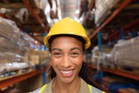 Portrait of happy female worker looking at camera in warehouse. This is a freight transportation and...