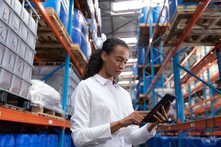 African American female manager using digital tablet in warehouse. This is a freight transportation and distribution warehouse. Industrial and industrial workers conceptの写真素材