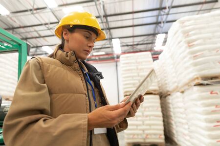 Low angle view of female worker using digital tablet in warehouse. This is a freight transportation...
