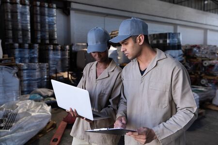 Front view of male and female worker discussing over laptop in warehouse. This is a freight...