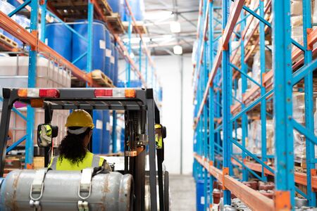 Rear view of female staff driving forklift in warehouse. This is a freight transportation and...