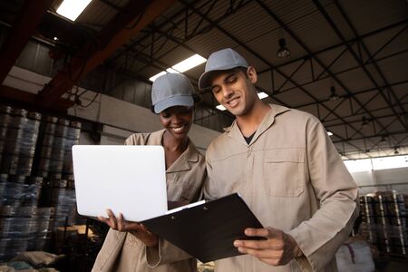 Low angle view of male and female worker discussing on clipboard in warehouse. This is a freight...