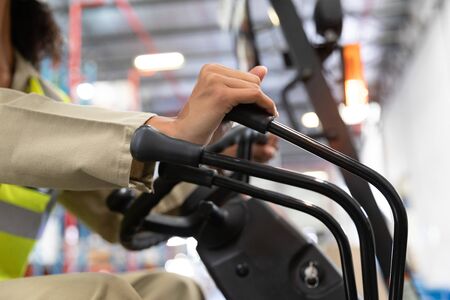 Close-up off female staff driving forklift in warehouse. This is a freight transportation and...