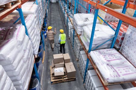 High angle view of female staff interacting with her coworker in warehouse. This is a freight...