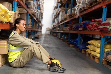 Tired female staff sitting on floor in warehouse. This is a freight transportation and distribution warehouse. Industrial and industrial workers conceptの写真素材