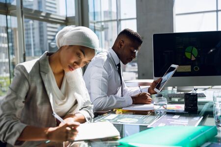 Male and females executives working together at desk in office. Modern corporate start up new business concept with entrepreneur working hardの写真素材