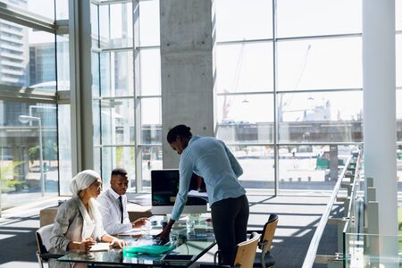 Male and females executives working together at desk in office. Modern corporate start up new...