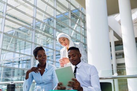 Male and females executives discussing over digital tablet at desk in office. Modern corporate start up new business concept with entrepreneur working hardの写真素材