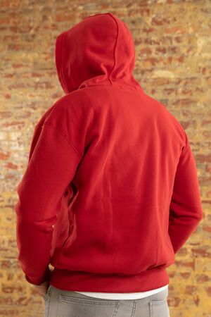 Rear view close up of a young Caucasian man wearing casual street fashion clothes standing against a...