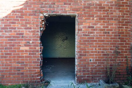 Exterior of an abandoned warehouse building, doorway and red brick wallの写真素材
