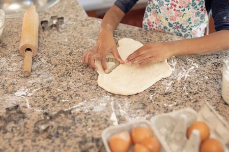 Side view mid section of a young mixed race girl in a kitchen at Christmas, making cookies and...