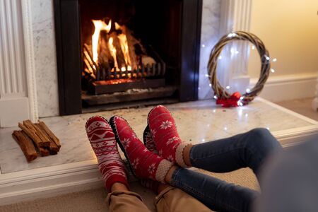 Legs of a mixed race couple in their sitting room at Christmas, lying on the floor by a fireplaceの写真素材