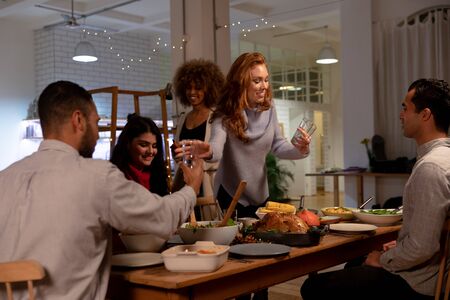 Front view of a group of five young adult multi-ethnic male and female friends sitting around a...