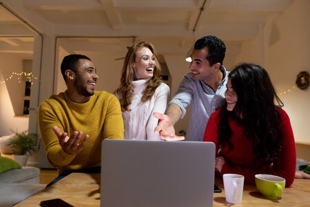 Front view close up of a group of four young multi-ethnic male and female friends looking at a...