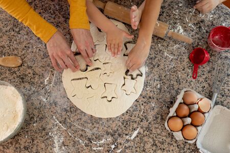 Overhead view of the hands of young Caucasian mother and her son and daughter in their kitchen at...