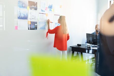 Side view of a Caucasian female business creative working in a casual modern office, standing and...