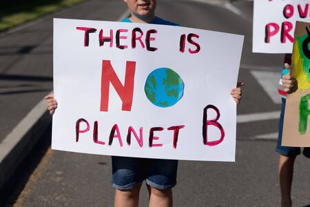 Front view mid section of a Caucasian elementary school boy on a protest march, carrying a sign with...
