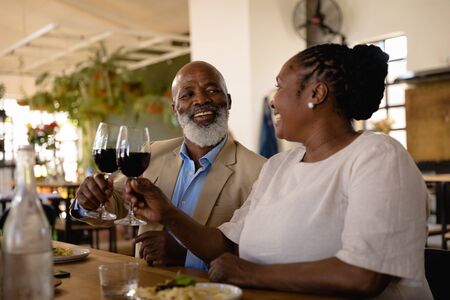 Side view of an Senior African man and an African woman at cookery class, making a toast. Active...